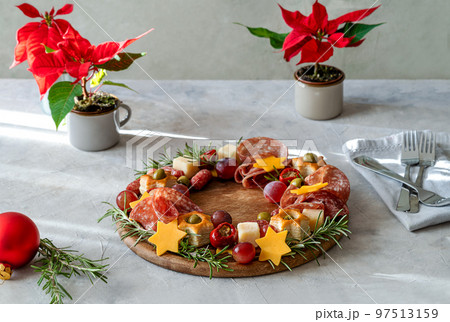 Christmas appetizers wreath on wooden board and grey background, star of Christmas plant or Poinsettia, napkin, forks Christmas appetizers wreath on wooden board and grey background, star of Christmas plant or Poinsettia, napkin, forks 97513159