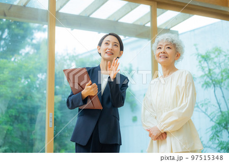 シニア女性に物件を案内するスーツの女性 97515348