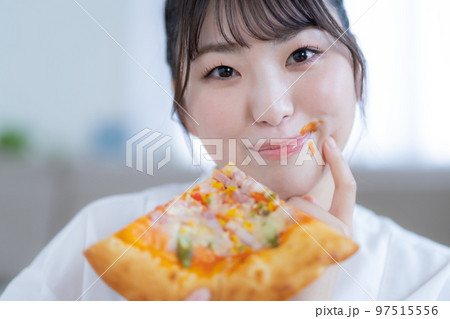 口元にケチャップをつけてピザを食べる若女性 口元にケチャップをつけてピザを食べる若女性 97515556