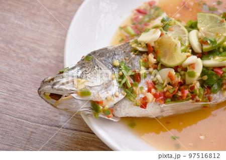 steamed bass fish dressing lemon sweet and sour chili sauce on plate steamed bass fish dressing lemon sweet and sour chili sauce on plate 97516812