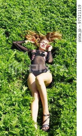 Beautiful young woman lies on the grass. Fresh natural summer concept. View from the top. 97521119