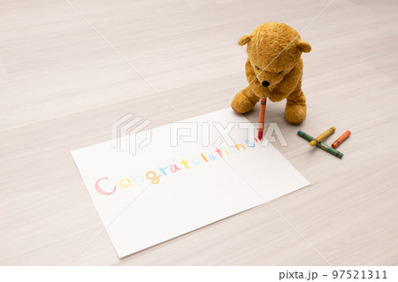 紙にクレヨンでCongratulationsと書く熊の縫いぐるみ 紙にクレヨンでCongratulationsと書く熊の縫いぐるみ 97521311