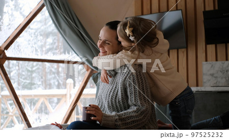 Little girl with mother enjoying winter vacation in geo dome glamping tent 97525232