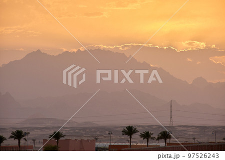 Sunset landscape with remote hotel complex against dark mountain peaks in egyptian desert 97526243