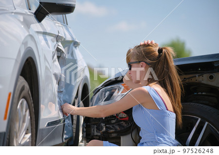 Stressed woman driver sitting on street side shocked after car accident. Road safety and insurance concept Stressed woman driver sitting on street side shocked after car accident. Road safety and insurance concept 97526248
