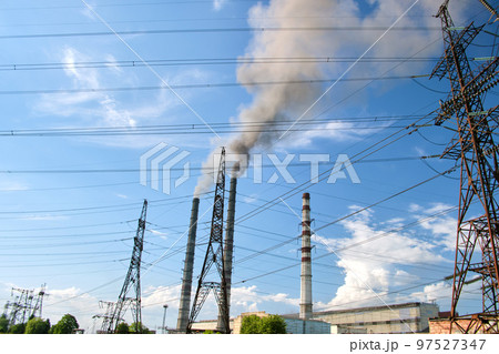 High voltage electric pylons against coal power plant high pipes with black smoke moving upwards polluting atmosphere. Production of electrical energy with fossil fuel concept 97527347