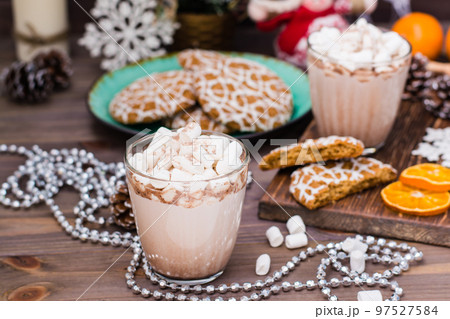 Hot cocoa with marshmallows in glasses and christmas cookies on a plate on the wooden table in Christmas decorations 97527584