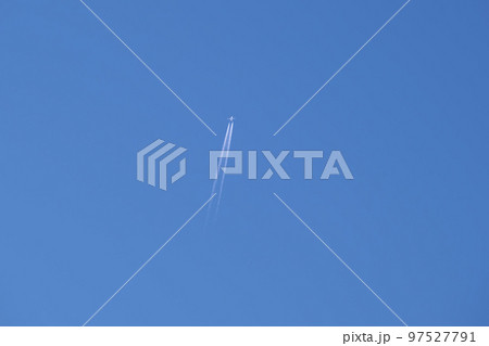 Distant passenger jet plane flying on high altitude on clear blue sky leaving white smoke trace of contrail behind. Air transportation concept. 97527791