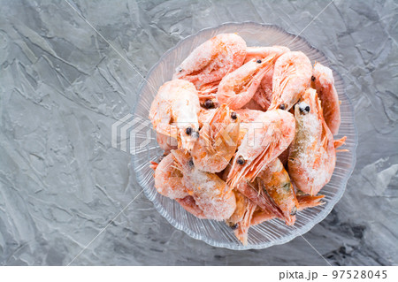 Group of frozen shrimp in a glass bowl on a gray table. Top view Group of frozen shrimp in a glass bowl on a gray table. Top view 97528045