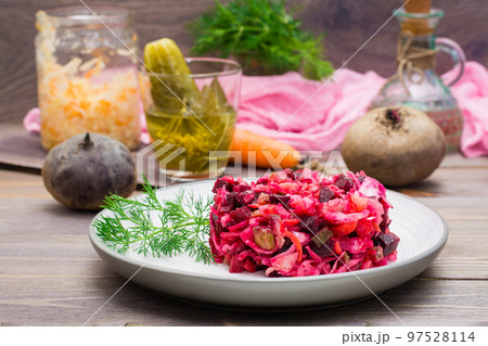 National Russian salad - vinaigrette - from boiled vegetables, sauerkraut and pickled cucumbers on a plate on a wooden table 97528114