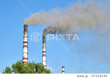 Closeup of thermal power plant high pipes with black smoke moving upwards polluting atmosphere. Production of electrical energy with fossil fuel concept 97528140