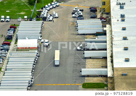 Big corporate shipment center with many cargo semi trucks unloading and uploading retail products for further retail shipment. Global market concept 97528819