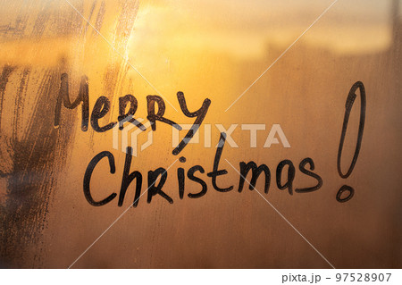 Words congratulation Merry Christmas on muddy wet orange window in city on sunset 97528907