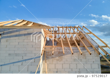 Aerial view of unfinished frame of private house with aerated lightweight concrete walls and wooden roof frame under construction. 97529017