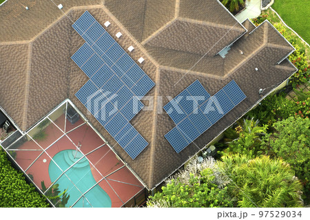 Aerial view of typical american building roof with blue solar photovoltaic panels for producing clean ecological electric energy. Investing in renewable electricity for retirement income concept Aerial view of typical american building roof with blue solar photovoltaic panels for producing clean ecological electric energy. Investing in renewable electricity for retirement income concept 97529034