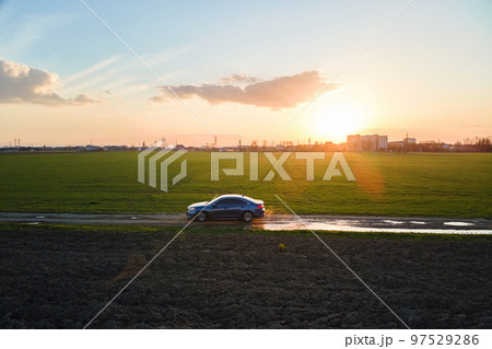 Aerial view of sedan car driving fast on dirt road at sunset. Traveling by vehicle concept. 97529286