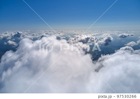 Aerial view from airplane window at high altitude of earth covered with puffy cumulus clouds forming before rainstorm. Aerial view from airplane window at high altitude of earth covered with puffy cumulus clouds forming before rainstorm. 97530266