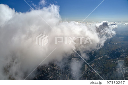 Aerial view from airplane window at high altitude of earth covered with puffy cumulus clouds forming before rainstorm. 97530267