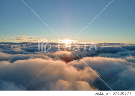 Aerial view from above at high altitude of dense puffy cumulus clouds flying in evening. Amazing sunset from airplane window point of view 97530277