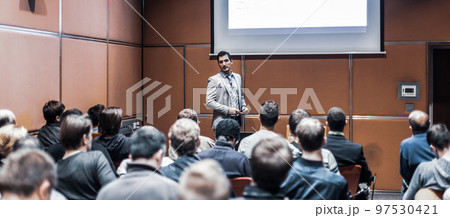 Speaker giving a talk in conference hall at business meeting event. Rear view of unrecognizable people in audience at the conference hall. Business and entrepreneurship concept. Speaker giving a talk in conference hall at business meeting event. Rear view of unrecognizable people in audience at the conference hall. Business and entrepreneurship concept. 97530421