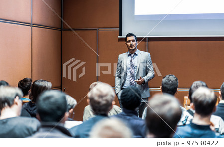 Speaker giving a talk in conference hall at business meeting event. Rear view of unrecognizable people in audience at the conference hall. Business and entrepreneurship concept. Speaker giving a talk in conference hall at business meeting event. Rear view of unrecognizable people in audience at the conference hall. Business and entrepreneurship concept. 97530422