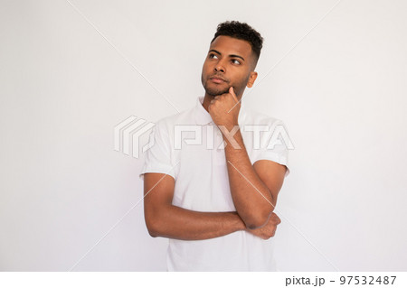 Portrait of pensive young man standing with hand on chin Portrait of pensive young man standing with hand on chin 97532487