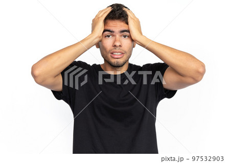 Frustrated young man pressing hands to head Frustrated young man pressing hands to head 97532903