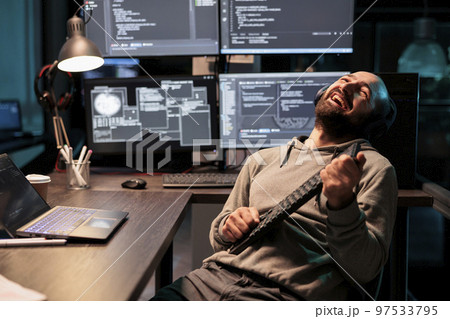 Cheerful programmer singing at air guitar keyboard late at night, working on cloud computing html script. Having fun with artificial intelligence and data on terminal window, fooling around. 97533795