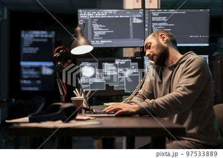 Software engineer talking on landline phone call after hours, answering office cord telephone to program code on terminal window. Database admin using phone line to develop new interface. 97533889