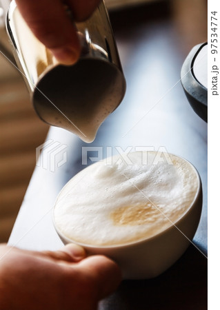 man pouring into a cup of coffee with milk man pouring into a cup of coffee with milk 97534774