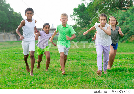 Five smiling kids running and laughing in park 97535310