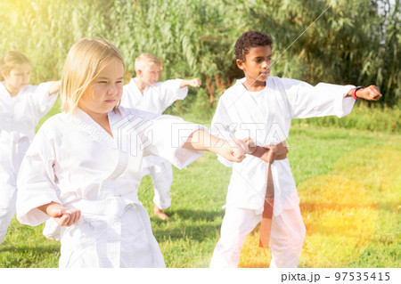 Positive children practicing karate in park 97535415