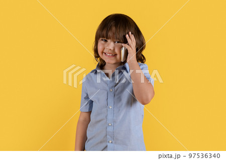 Mobile connection anywhere. Adorable little boy talking on cellphone with far living family or friend, smiling to camera Mobile connection anywhere. Adorable little boy talking on cellphone with far living family or friend, smiling to camera 97536340