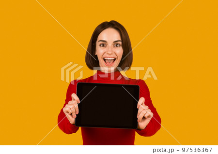 Excited attractive lady showing digital tablet with blank screen Excited attractive lady showing digital tablet with blank screen 97536367