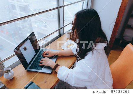 カフェでテレワークをしている若い女性の写真 97538265