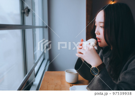 家でドーナツを食べる若い女性の写真 97539938