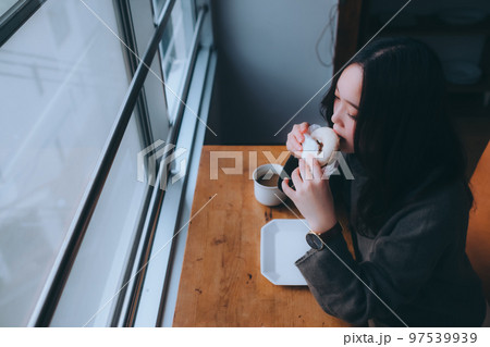家でドーナツを食べる若い女性の写真 97539939