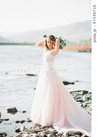 Portrait of stunning bride with long hair standing by the river Portrait of stunning bride with long hair standing by the river 97540716