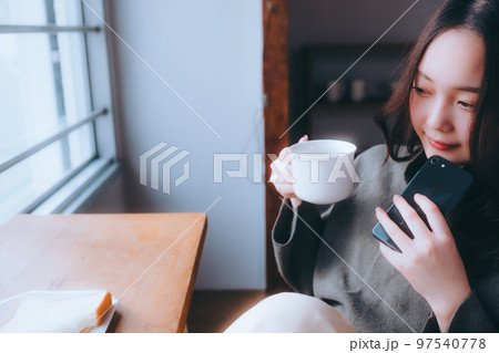 部屋で朝食を食べる若い女性の写真 97540778