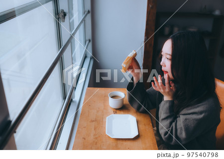 部屋で朝食を食べる若い女性の写真 97540798