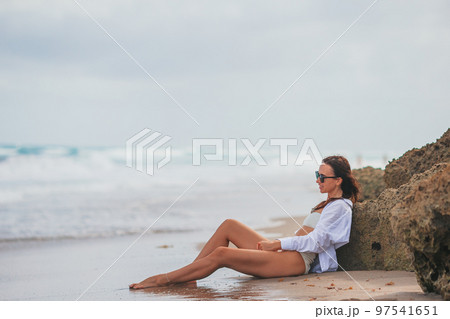 Young happy woman on the beach enjoy her summer vacation. Girl is happy and calm in her stay on the beach Young happy woman on the beach enjoy her summer vacation. Girl is happy and calm in her stay on the beach 97541651