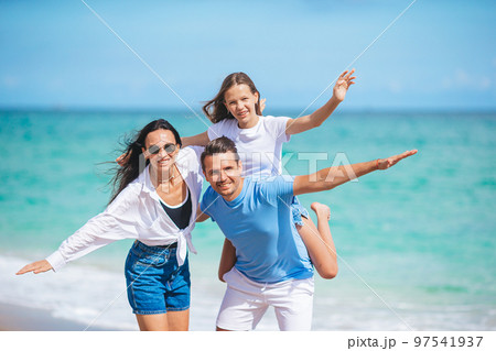 Family of three on the beach having fun together Family of three on the beach having fun together 97541937