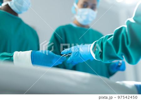 Low angle of surgeons passing surgical tools in operating theatre during operation, with copy space 97542450
