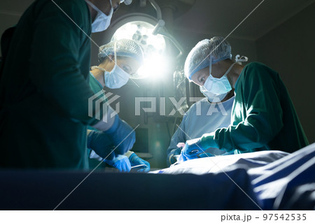 Diverse group of female and male surgeons operating on patient in operating theatre Diverse group of female and male surgeons operating on patient in operating theatre 97542535