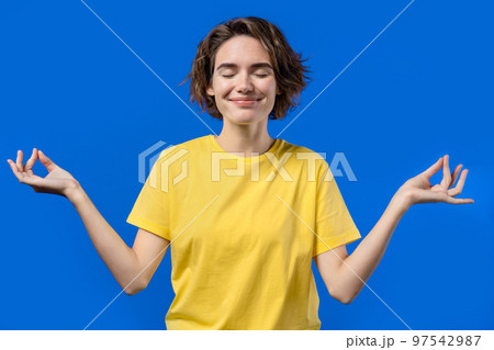 Calm woman relaxing, meditating, refuses stress. Sunny girl breathes deeply, calms down blue studio Calm woman relaxing, meditating, refuses stress. Sunny girl breathes deeply, calms down blue studio 97542987