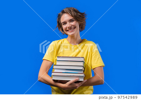 Clever student woman holds stack of university books from college library on blue background. Happy Clever student woman holds stack of university books from college library on blue background. Happy 97542989