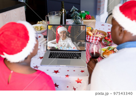 Senior african american couple having christmas video call with biracial woman 97543340