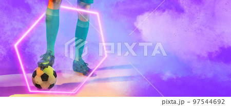 Low section of male player with leg on soccer ball over illuminated hexagon against smoke 97544692