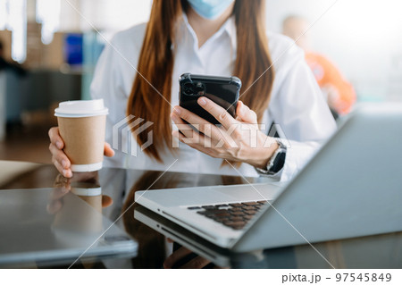 businesswoman typing laptop computer and digital tablet while holding coffee 97545849