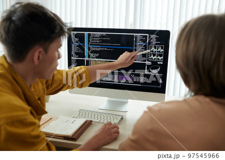 College students working on project together and discussing programming code and chart on screen 97545966